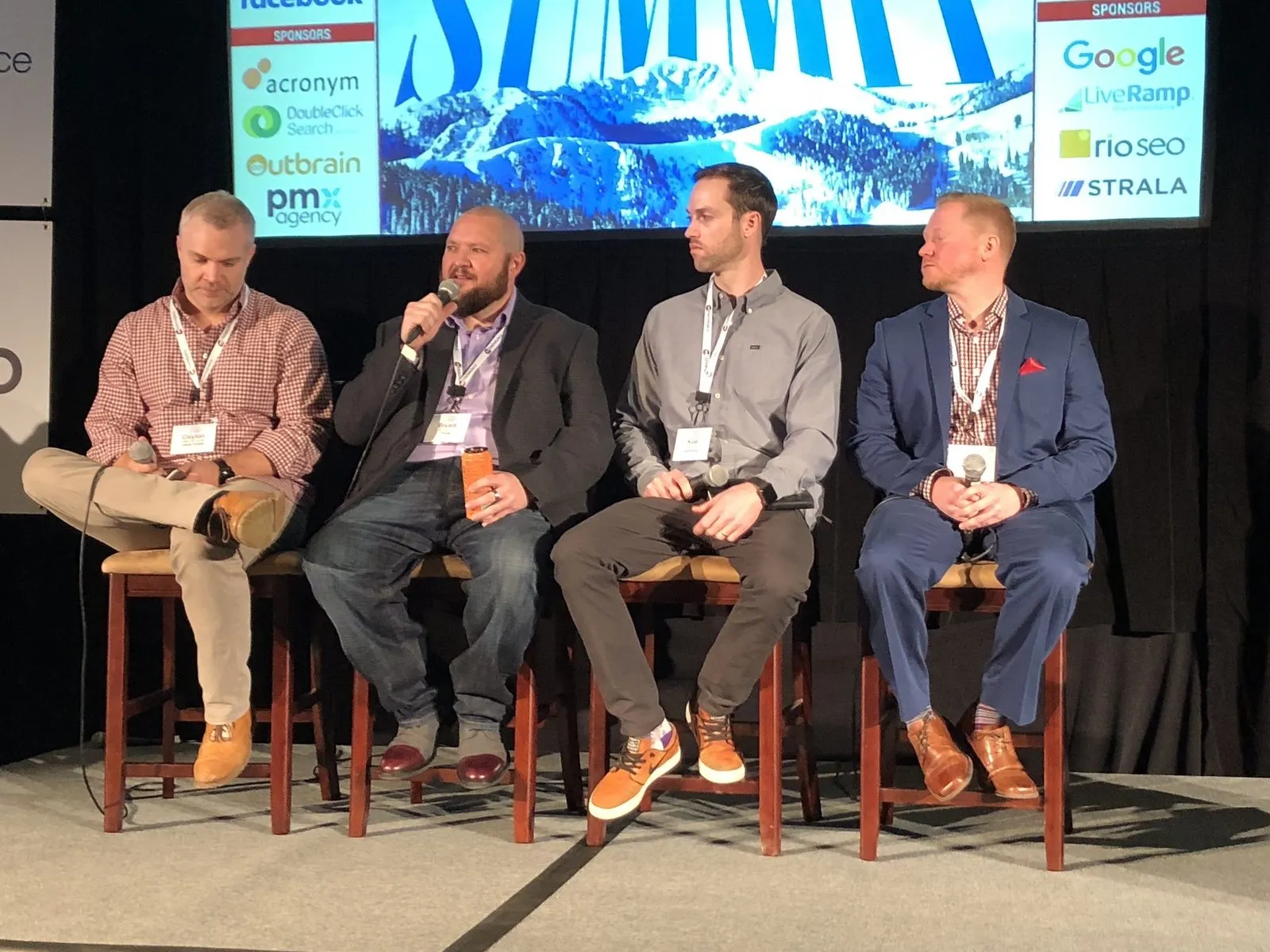 Bryant Garvin, second from left, holding the microphone during a four-person panel at MediaPost Search Insider Summit.